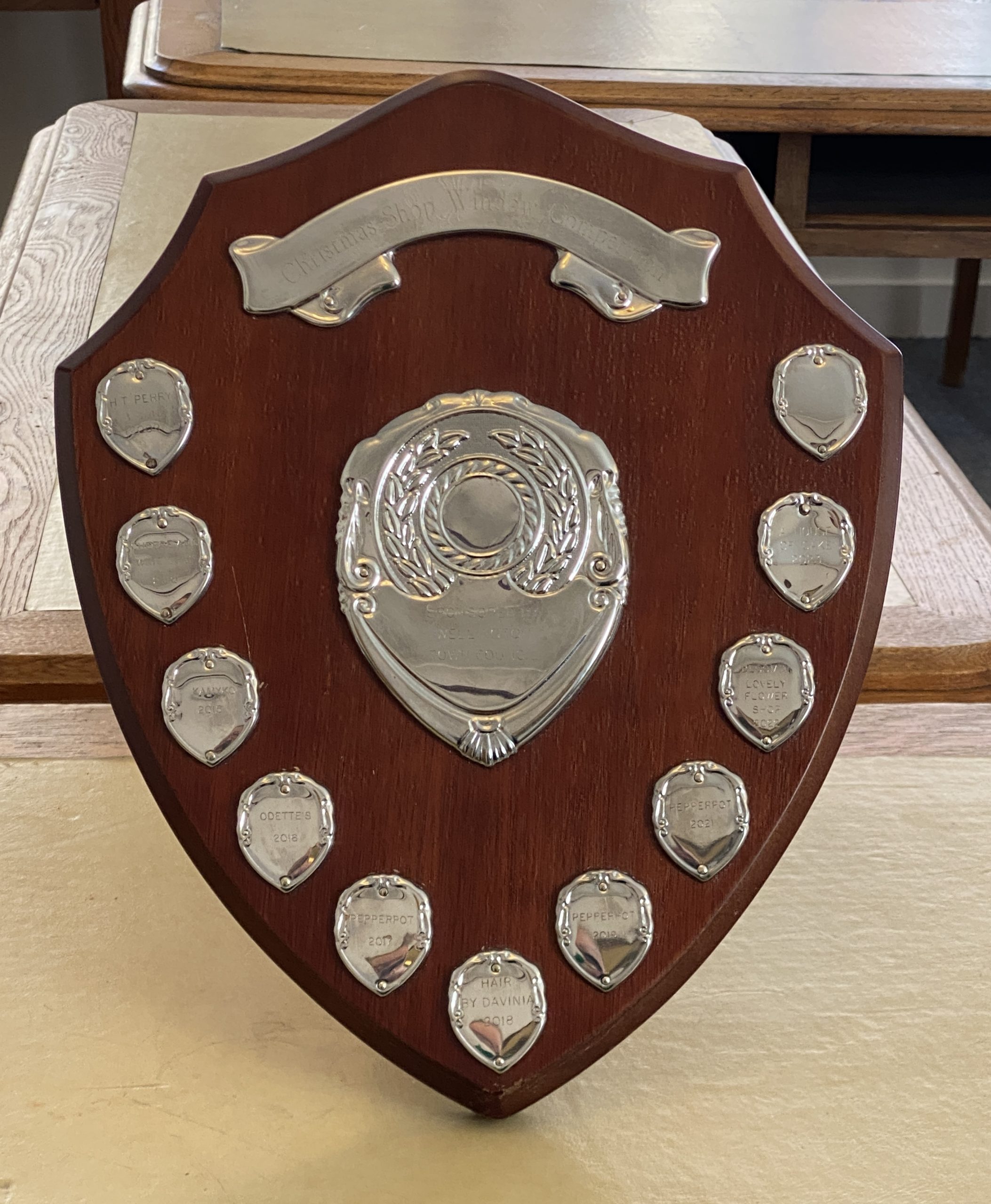 A wooden award shield with silver medallions.